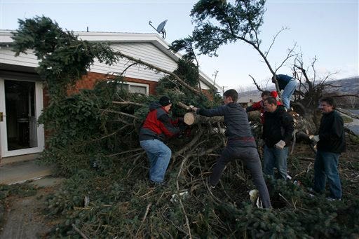 Neighbors help remove a tree that toppled onto the house of Don and Louise Lochhead in Bountiful, Utah, Thursday, Dec. 1, 2011. High winds ripping through Utah have overturned several semi-trucks, knocked out power to more than 50,000 customers and prompted school closures.
