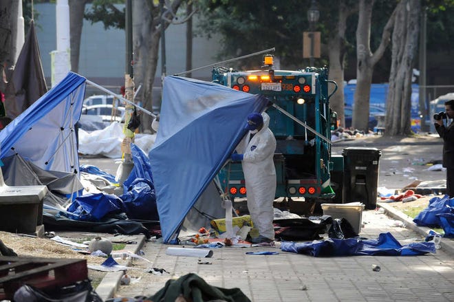 Los Angeles city sanitation workers clean up the aftermath of the Occupy Los Angeles movement Wednesday after the Los Angeles police broke up the large encampment of protesters who had been camping out for the past two months at City Hall.