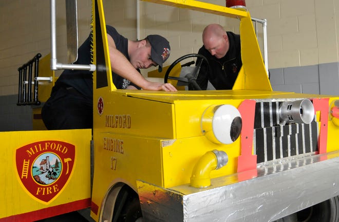 Milford firefighters Don Martino, left, and Jim Curley put finishing touches on the mini fire truck that will be in Sunday's Santa Parade in Milford.