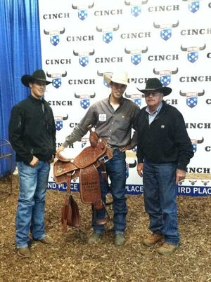 Receiving congratulations from his brother, Ryan Domer, and his grandfather, Bob Domer, Collin Domer, of Topeka, collectes this trophy saddle and checks totaling $28,300 at the U.S. Team Roping Championships Finals in Oklahoma City.