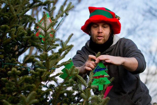 John Marshall hangs ornaments on the Christmas tree during the annual Holiday on the Common in Natick Sunday afternoon.