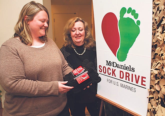 McDaniels Marketing director of public relations Brenda Tomlinson and art director Samantha Preston display some socks that have been collected in the Sock Drive for Marines, which runs until Jan. 6, at the 11 Olt Ave. offices.