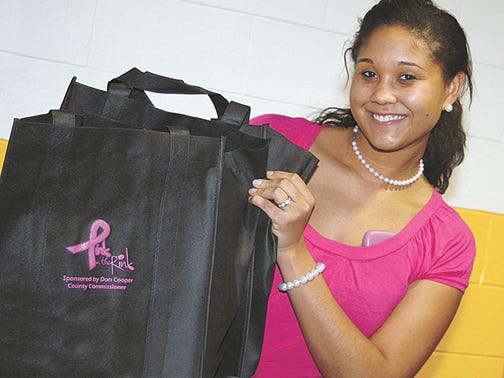 LSSU Alpha Theta Omega sorority member Karizma Vance shows off a freshly-stuffed "Pink in the Rink" gift bag. Vance's sorority helped the hockey team prepare the bags on Dec. 7 for an annual benefit game coming up this weekend to benefit breast cancer research. Fans attending tonight’s game will receive a pink rally towel and one raffle ticket for a chance to win one of 50 gift baskets. The first 250 fans to arrive at Saturday's hockey game will receive the free goodie bags.