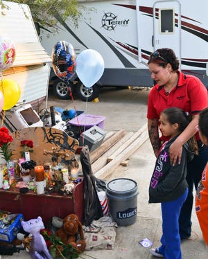 Naomi Salinas and her daughter Jannette visit a shrine for Rachelle, Timothy and Ramie Grimmer in front of the family's RV in Laredo. Authorities say Rachelle Grimmer shot her children and then killed herself in a Laredo welfare office Monday following a seven-hour standoff with police.