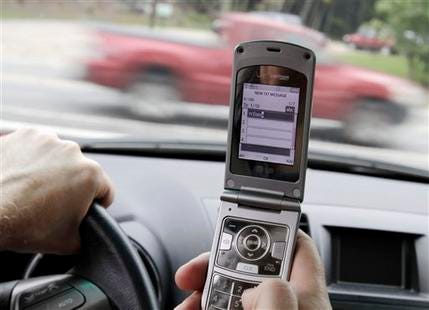 FILE - In this Sept. 20, 2011 file photo, a phone is held in a car in Brunswick, Maine. Texting, emailing or chatting on a cellphone while driving is simply too dangerous to be allowed, federal safety investigators declared Tuesday, Dec. 13, 2011, urging all states to impose total bans except for emergencies.