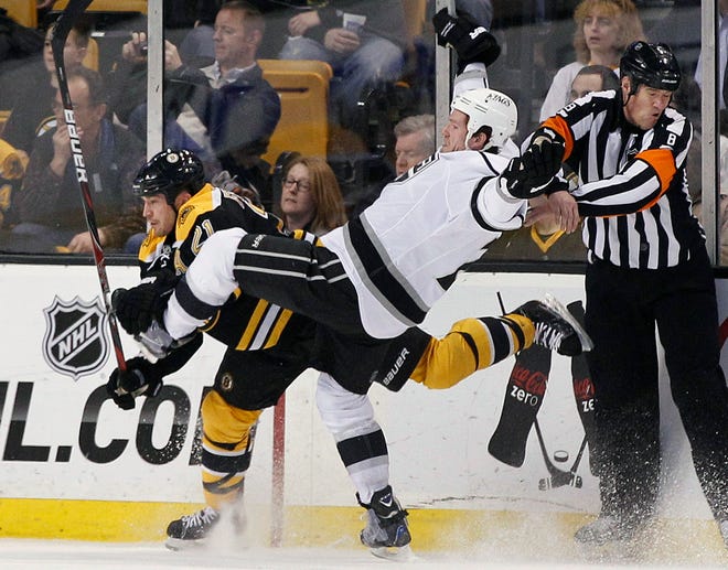 Los Angeles Kings center Colin Fraser (24) goes flying after colliding with Boston Bruins defenseman Andrew Ference (21) as referee Dave Jackson (8) protects himself in Boston on Tuesday, Dec. 13, 2011.
