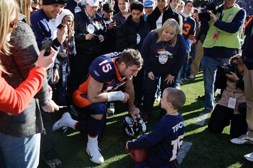 Denver Broncos quarterback Tim Tebow (15) talks to a young fan before the start of an NFL football game against the Chicago Bears, Sunday, Dec. 11, 2011, in Denver.