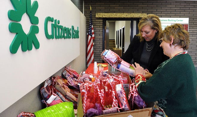 Donna Farrell, senior vice president of Citizens Bank on Main Street in Stroudsburg, left, helps Sharon Taylor, director of Pocono Area Transitional Housing, load toiletries and other items collected by bank customers and employees into stockings.