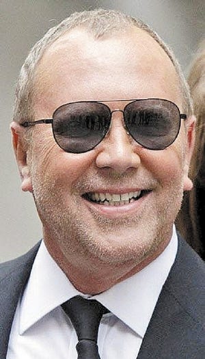 Fashion designer Michael Kors poses for photos in front of the New York Stock Exchange.