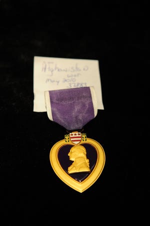 Bryan VanDenBosch displays a Purple Heart that a solider sold for extra cash around the holidays at his pawn shop, A to Z Pawn Shop, on North River Avenue.