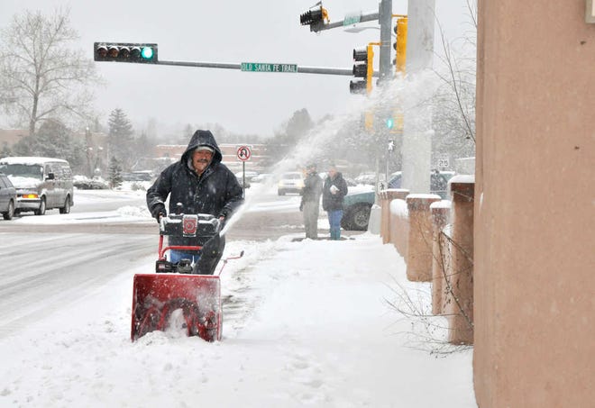 Sidewalks get cleared along the Paseo de Peralta in Santa Fe, N.M. as Santa Fe residents deal with the winter storm that hit Monday Dec. 19, 2011. New Mexico state police say a winter storm is shutting highways and causing difficult driving across northern New Mexico. Los Alamos National Laboratory and a number of schools have closed as the storm moves across New Mexico and into the Texas and Oklahoma Panhandles and parts of Kansas and Colorado.  (AP Photo/The New Mexican, Clyde Mueller)
