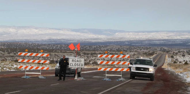 Sandoval County Sheriff's Deputy Phillip Montano mans a roadblock along U.S. 550 near Rio Rancho, N.M., on Friday. Another blast of winter weather has socked New Mexico, closing parts of major highways and canceling flights for holiday travelers.