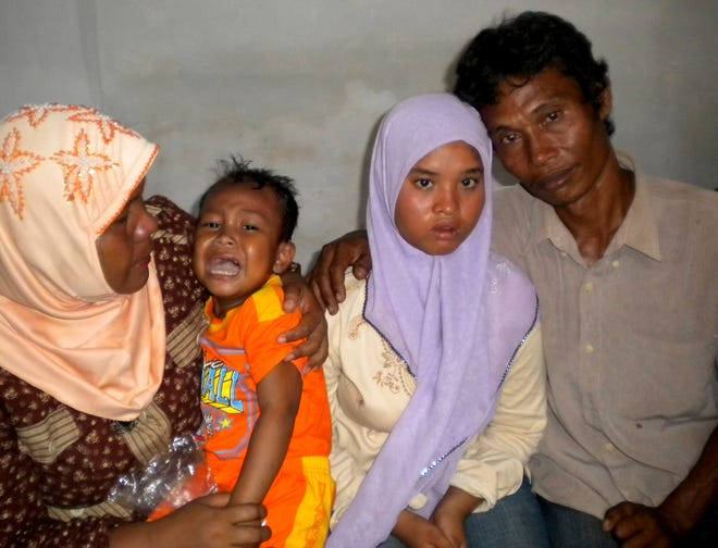Fifteen-year-old Wati, second right, poses for a photograph with her father Yusuf, right, mother Yusniar, left, and younger brother Aris at their home in Meulaboh, Aceh province, Indonesia.