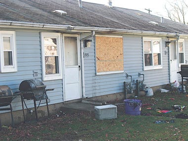 A boarded up window and scattered, heat-damaged debris in the yard remain from a Christmas Eve fire that drove members of a Pekin family from their home and destroyed most of their possessions.