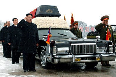 The casket of Kim Jong-il, who hated the United States, sat atop an American-made Lincoln Continental. The next leader, Kim Jong-un, is at left.