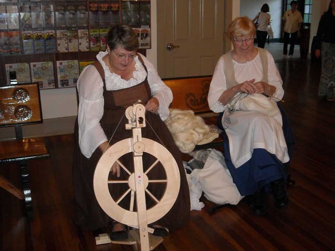 Celeste Burns spins on a wheel as Reba Anderson knits the finished product in celebration of St. Distaff's Day. Contributed photo.