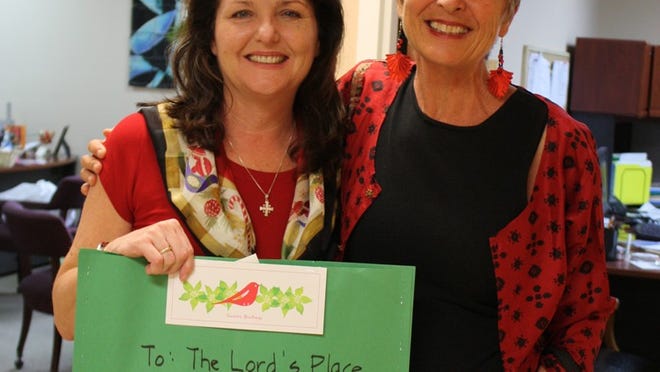 Diana Stanley, left, executive director of The Lord’s Place, receives a holiday card created by Palm Beach Public elementary school students on Dec. 22 from Leslie Drinkovic.