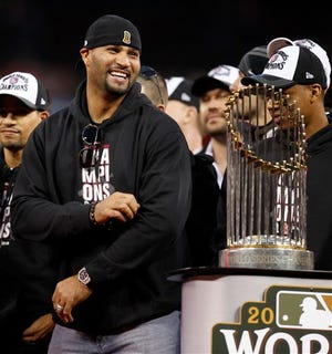 St. Louis Cardinals first baseman Albert Pujols smiles next to the World Series trophy during a celebration of the baseball team's 11th World Series title, Sunday, Oct. 30, 2011, in St. Louis. (AP Photo/Jeff Roberson)