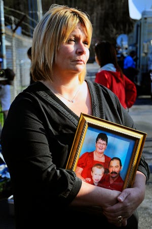 In this April 6, 2010 file photo, Michelle McKinney talks to the media outside of Marsh Fork Elementary while holding a family photo of her father, Benny Willingham, mother Edith Willingham and grandson McQuade Canada, in Naoma, W.Va. McKinney's father Benny Willingham, 61, of Corinne, W.Va., was killied in an explosion at Massey Energy's Upper Big Branch Coal Mine. The mining company has settled wrongful death lawsuits with families of all 29 victims of the Upper Big Branch disaster on Tuesday, Jan. 10, 2012. Details of the agreement were not released. (AP Photo/Jeff Gentner, File)
