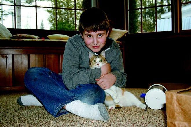 Ten-year-old Tyler holds a relaxed Nala in the living room of his grandparents, Bob and Sue Darnell. The family adopted the kitty after it was found with a rope embedded in its neck and rescued by the Northern Michigan Animal Rescue Network.
