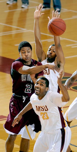 West Texas A&M's Kennon Washington (2) passes between Midwestern State defenders JaMichael Rivers (23) and Kevin Grayer in their Lone Star Conference men's game Wednesday night in Wichita Falls. MSU won in overtime, 66-60.