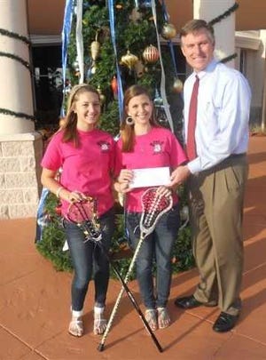 Flagler Palm Coast High School varsity girls lacrosse players Nicole Madalena, 16, and Katia Zintchenko, 15, donated $200 to John Subers, Florida Hospital Flagler Foundation and marketing director. The varsity girls lacrosse team made and sold T-shirts to raise money and awareness for local women battling breast cancer. Contributed photo.