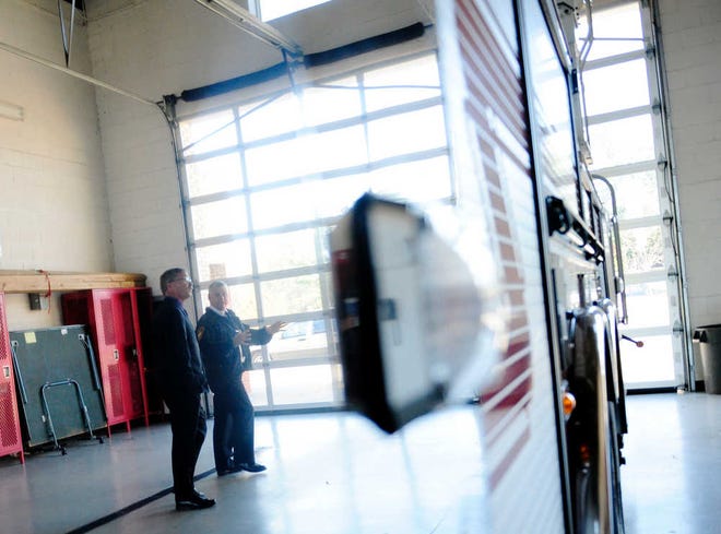 Reflections are seen in the side of a fire truck of fire chief candidate Glenn Jones (left) and Operations Chief Wayne Taylor as they tour Engine House No. 8.