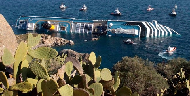 Rescue boats approach the luxury cruise ship Costa Concordia resting on its starboard side after running aground near the tiny Tuscan island of Isola del Giglio, Italy, on Saturday. The luxury cruise ship ran aground off the coast of Tuscany, sending water pouring in through a 160-foot gash in the hull and forcing the evacuation of some 4,200 people from the listing vessel early Saturday, the Italian coast guard said. In the background Italy's mainland.