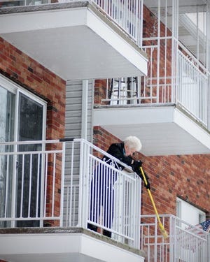 Sandy Sera of Cavalier Condos on Sims Street in Ellwood City
brushes snow off her balcony Friday morning.