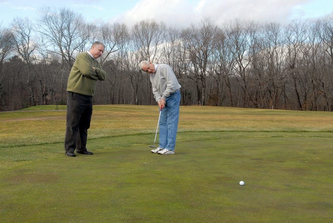 Norwich Golf Course golf pro Mike Svab looks on as Danny Quintiliani Jr. practices his putts Friday morning.