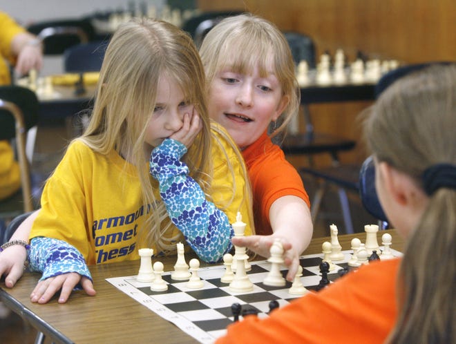 Aarika Rex of Clearmont School, sits on the lap of Alexa Hurst of Northwood School as she makes a chess move against Tess Cunningham. Hurst and Cunningham are both fifth graders while Rex is a first grade student.