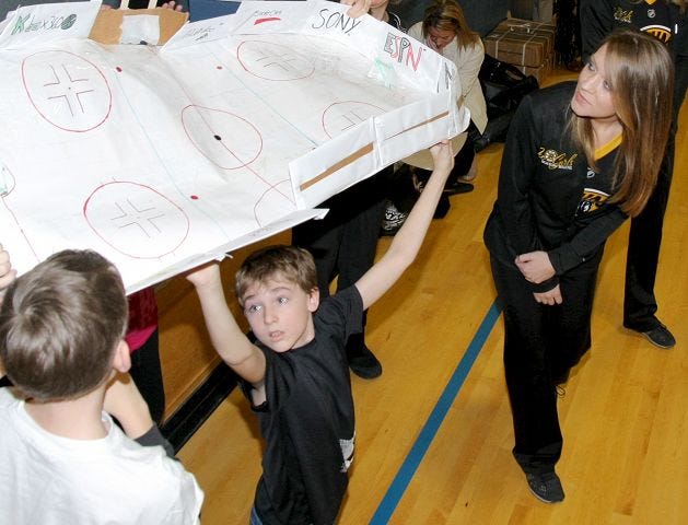 EJ Hersom/Staff photographer Boston Bruins Ice Girl Kelly Thomson looks at an ice rink being held up by Somersworth Middle School student Hunter Breslin in Somersworth Wednesday.