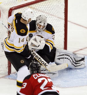 Boston Bruins goalie Tim Thomas makes a save with help from Joe Corvo (14) on a shot by New Jersey Devils' David Clarkson (23) during the second period of an NHL game in Newark, N.J., Thursday, Jan. 19, 2012. Boston won 4-1.