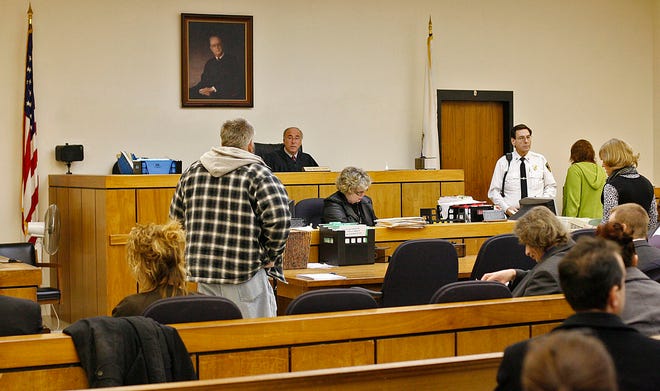 Judge Mark Coven, center, listens to a defendant explain why he is late on paying money to the court.