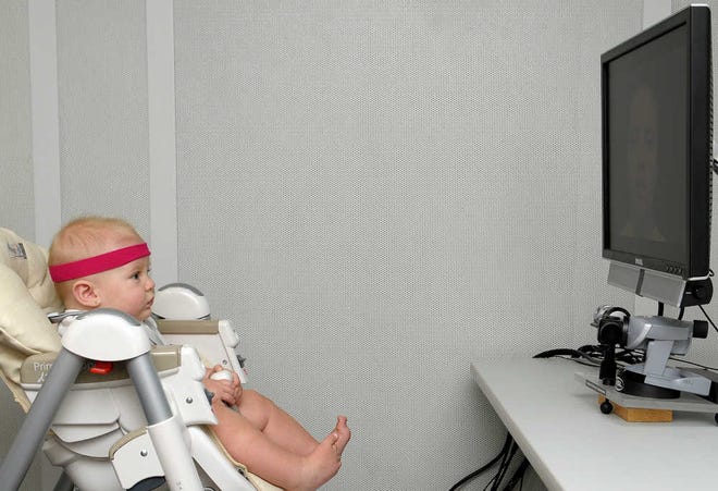This undated handout photo provided by Florida Atlantic University shows a baby, looking at a monitor, wearing a band that contains a little magnet that the head-tracker, under the monitor uses to determine head position which, in turn, enables the eye tracker to find the eye and the pupil. New research suggests babies don't learn to talk just from hearing sounds _ they're lip-readers, too. It happens during that magical stage when a baby's babbling gradually changes from gibberish into syllables and eventually into that first "mama" or "dada." (AP Photo/Florida Atlantic University)