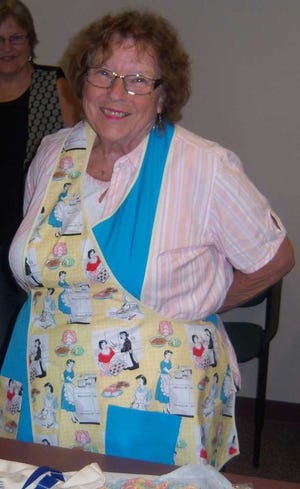 Pat Meyer shows an apron she made using fabric from the group's annual yard sale. Contributed photo.