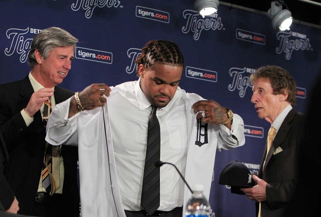 THIS CORRECTS THE SPELLING OF THE LAST NAME TO DOMBROWSKI, AND NOT DOMBROSKI AS ORIGINALLY SENT - Detroit Tigers president, CEO and general manager Dave Dombrowski, left, helps new Tigers first baseman Prince Fielder with his uniform as team owner Mike Ilitch looks on during a baseball news conference at Comerica Park in Detroit, Thursday, Jan. 26, 2012. Fielder agreed to a $214 million, nine-year contract with the Tigers. (AP Photo/Carlos Osorio)