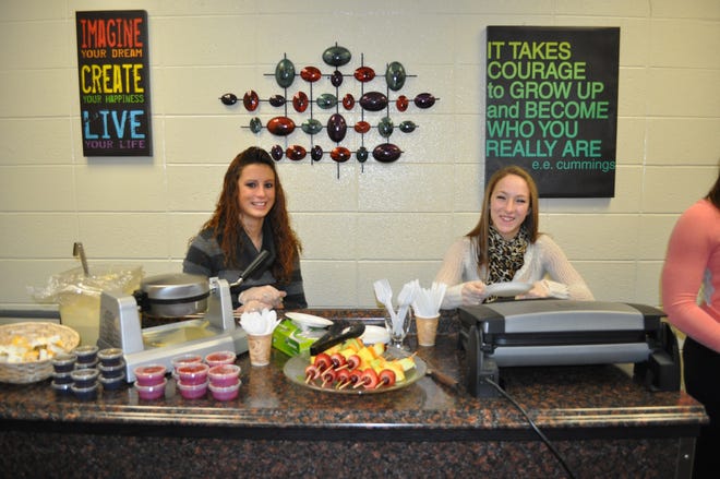 Senior Leadership students Laurie DeMars and Jaclyn Orangio, both of Maynard, serve waffles, fruit skewers and hot paninis at the newly opened Cyber Café in the Assabet Valley Regional Technical High School Media Center.