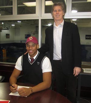Pope John senior Malachi Moore (seated, left) signs his letter of intent Wednesday to play football for Boston College. Also pictured is current Lions football coach Brian Carlson.