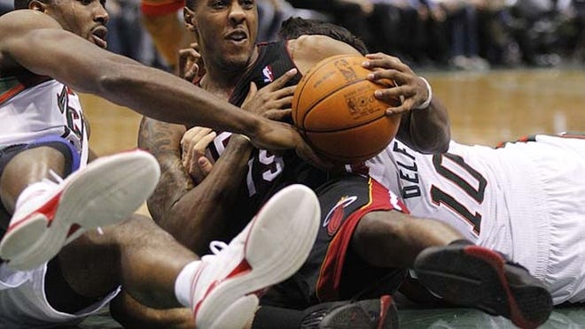 Milwaukee Bucks' Luc Richard Mbah A Moute, left, Miami Heat's Mario Chalmers (15) and the Bucks' Carlos Delfino (10) wrestle for a loose ball during the second half of an NBA basketball game on Wednesday, Feb. 1, 2012, in Milwaukee. The Bucks won 105-97. (AP Photo/Jeffrey Phelps)