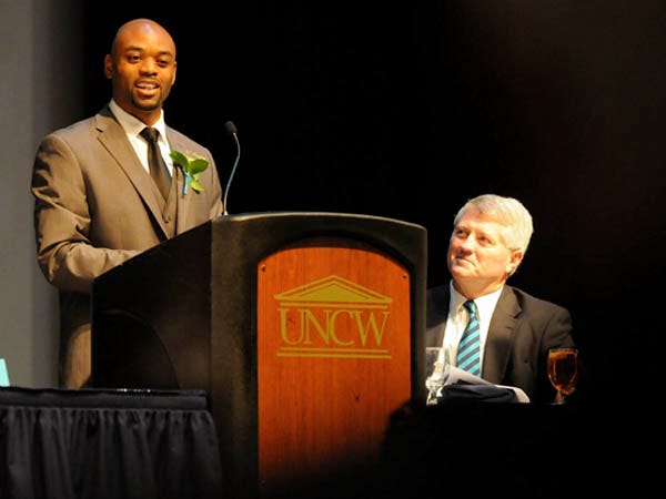 Xzavier Chisholm speaks during the 9th annual UNCW Athletic Hall of Fame Induction Ceremonies in the Warwick Center at UNCW Saturday as Athletic Director Jimmy Bass watches.