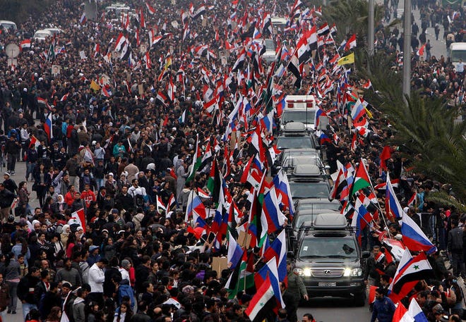Pro-Syrian regime supporters wave Syrian and Russian flags Tuesday as they cheer a convoy believed to be transporting Russian Foreign Minister Sergey Lavrov in Damascus, Syria. Lavrov arrived in Damascus for talks with embattled President Bashar Assad on the country's escalating violence.