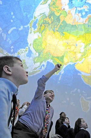 St. Mary’s Primary School first-grader Tyler Rose, left, looks up as Bridgewater State University Professor Vernon Domingo talks to the students about geography from inside an inflatable globe.