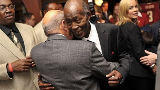 Leonard Levy, back to camera, hugs his longtime friend Freddie Solomon, who played quarterback at the University of Tampa and wide receiver in the NFL, on Wednesday, Nov. 30, 2011, in Tampa, Fla. Solomon attended a reception at the university before heading to Falk Theatre to see a documentary made by NFL Films, "The Legend of Freddie Solomon."