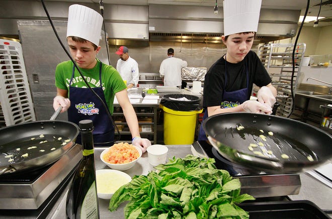 Bellingham Middle School eighth-graders Nick Dulac, left, and Dylan Boucher prepare ingredients for freestyle lasagna yesterday during a tour of Gillette Stadium's kitchen. Students were awarded the trip after contributing the winning video for the "Fuel Up to Play 60" challenge.