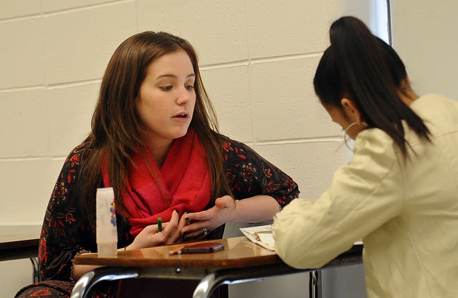 Milford High School teacher Amanda Laut works with sophomore Tanishalys Cruz-Gomez during a Pathways program English class.  The class is reading "The Hunger Games."