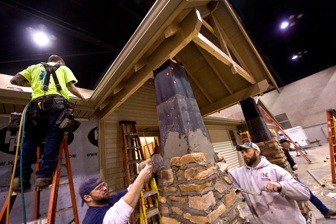 Nussbaum masons Matt Rigsby, center, and Derek Golden, right, join workers from Homeway Homes to build a full-size ranch home inside the Peoria Civic Center exhibit hall for the Spring Home Show. The home arrived in halves, and then was set on a temporary foundation, a roof was built on top and then workers put on shingles, siding, flooring, and masonry before painting and other finish work to make it complete. The home show runs Friday, Feb 25 from 4pm-9pm, Saturday, Feb 26 10am-8pm 
and Sunday, Feb 27 11am-4pm.
