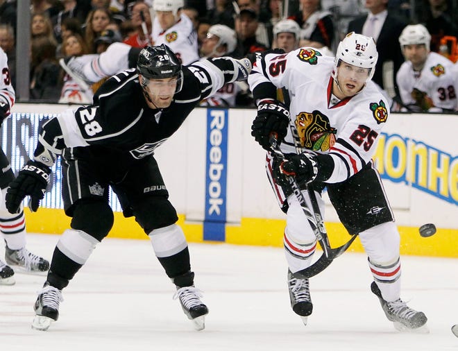 Chicago Blackhawks left wing Viktor Stalberg (25), of Sweden, sends the puck upice with Los Angeles Kings center Jarret Stoll (28) defending during the first period of an NHL hockey game in Los Angeles, Saturday, Feb. 25, 2012.