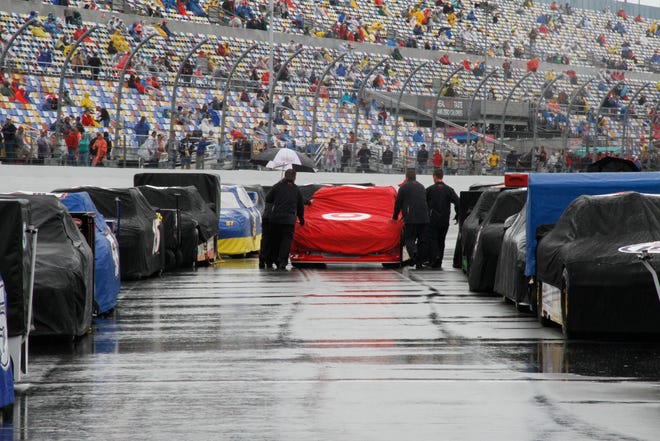 Crew members push a car to the starting grid before Sunday's scheduled Daytona 500. Persistent rain forced NASCAR to push the biggest race of its season to Monday, the first time in the event's 54-year history that it didn't run on a Sunday.