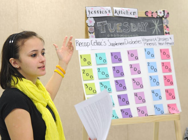 Stonehill College student Tara Daniels, 19, explains the board of the nutrition-themed Jeopardy! game.